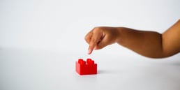 Childs hand pointing at a lego block